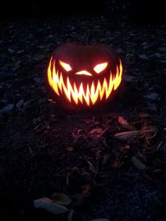 a carved pumpkin with glowing eyes on the ground