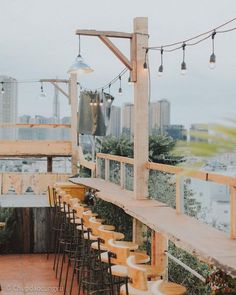 an outdoor bar with lots of chairs and lights hanging from the ceiling over it's tables