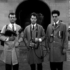 three men standing next to each other in front of a building