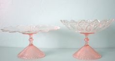 two pink glass dishes sitting on top of a table