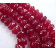 red glass beads are lined up on a white surface