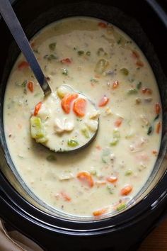 a spoon full of soup in a crock pot with broccoli and carrots