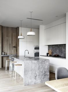 a kitchen with marble counter tops and stools next to an island in the middle