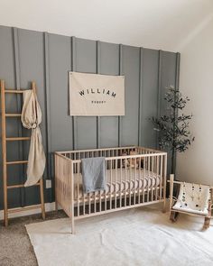 a baby's room with a wooden crib, ladder and blanket on the wall