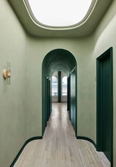 an empty hallway with green walls and wooden floors is seen in this image from the inside