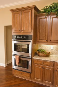 a kitchen with wooden cabinets and stainless steel ovens