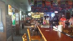 people are standing at the bar in a fast food restaurant with many signs hanging from the ceiling