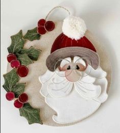 a christmas ornament with a santa clause on it and holly wreath around it