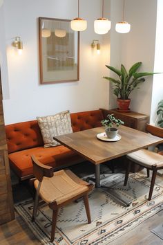 a living room filled with furniture and a wooden table surrounded by potted plants on top of a rug