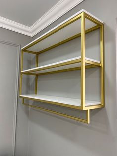 a gold and white shelving unit hanging on the wall