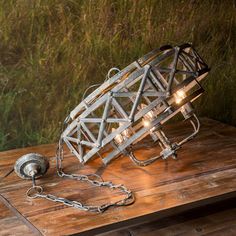 a metal object sitting on top of a wooden table next to a chain link light