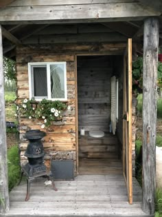 an outhouse with a wood stove and potted plants on the outside porch area