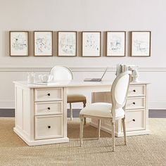 a white desk with two chairs and pictures on the wall