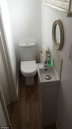 a white toilet sitting next to a sink in a bathroom under a window above a mirror