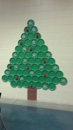 a christmas tree made out of green paper plates on a blue floor in front of a white wall