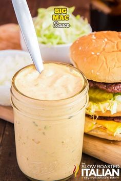 there is a large hamburger next to a jar of sauce