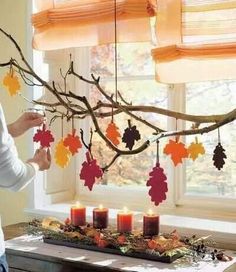 a woman standing in front of a table with candles and decorations hanging from the branches