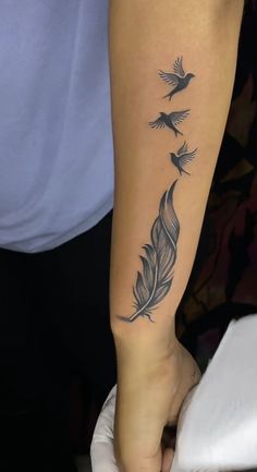 a person with a tattoo on their arm holding a white glove and some birds flying in the sky