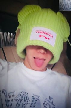 a young boy wearing a green hat and sticking his tongue out