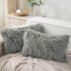 two gray furry pillows sitting on top of a bed