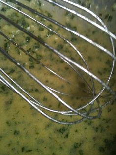 a metal whisk in a bowl filled with broccoli and cheese sauce