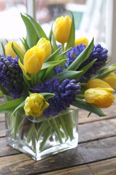 a glass vase filled with yellow and purple flowers