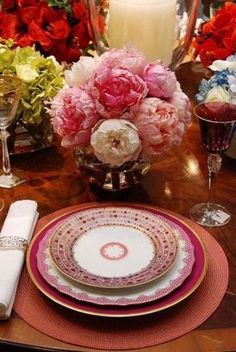 the table is set with plates and flowers in vases, candles, and napkins