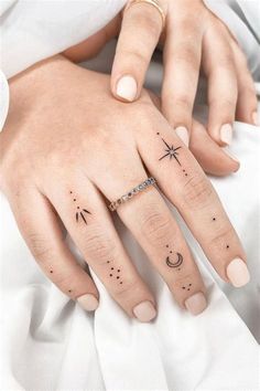 two fingers with stars and moon tattoos on them