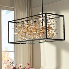 a chandelier hanging over a dining room table with flowers in the vases