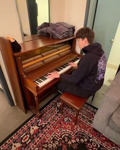 a young man sitting at a piano in front of a mirror with his hands on the keys