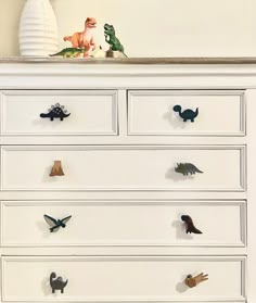 a white dresser with dinosaur knobs on it