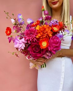 a woman holding a bouquet of colorful flowers