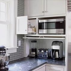 a kitchen with white cabinets and black counter tops, stainless steel appliances in the corner