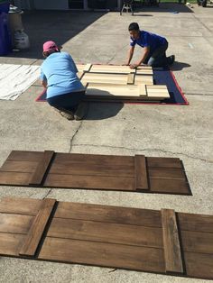 two men working on wood planks laying on the ground