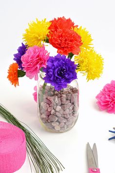 colorful flowers in a glass jar surrounded by scissors