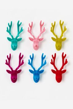 four different colored deer head magnets on a white surface