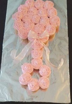 a cupcake with pink frosting and bows on it sitting in a plastic bag