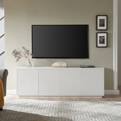 a flat screen tv sitting on top of a white cabinet