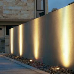 some lights are lit up on the side of a wall in front of a building