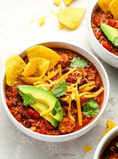 two bowls filled with chili, cheese and tortilla chips