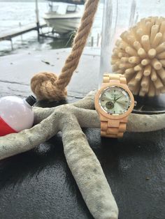 a wooden watch sitting on top of a table next to an object in a vase