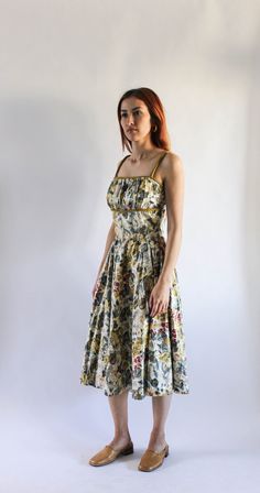 "DETAILS ◦ Vintage 1950s floral dress ◦ Cream color with light pinks, blues, greens, olive color floral print ◦ Fitted bodice, shelf bust with olive trim under chest and spaghetti straps ◦ Full, gathered skirt ◦ Metal zipper on left side ◦ Not lined No Size Labeled Best Fit / Estimated Size | Small Measurements | Bust - 32\" Waist - 24.5 \" - 25\" Bodice Length - 16\" Skirt Length - 27\" Tag/Label | None, appears handmade Material | Polished cotton, fabric has sheen. Condition | Very good. Zippe Fitted Midi Dress With Floral Print And Full Skirt, 1950s Floral Print A-line Dresses, 1950s Style Floral Print A-line Dress, 1950s Style A-line Floral Print Dress, 1950s A-line Dresses With Floral Print, Green Dress With Gathered Full Skirt, Green Dress With Gathered Skirt, Vintage Daywear Dresses With Gathered Skirt, Vintage Cotton Midi Dress For Garden Party