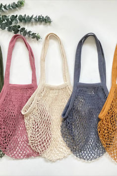 three different colored bags sitting next to each other on a white surface with greenery