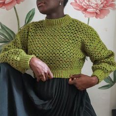 a woman wearing a green sweater and black skirt