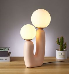 a lamp that is on top of a table next to a potted cacti