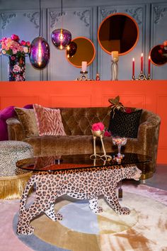 a leopard print coffee table in front of a couch with candles on it and other decorations