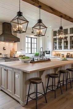 a large kitchen island with four stools and lights hanging from it's ceiling