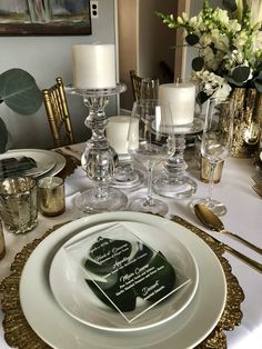 the table is set with white and gold place settings