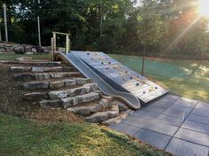 a slide that is in the middle of some rocks and grass with trees in the background