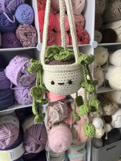 a crocheted planter hanging from the ceiling in front of some yarns